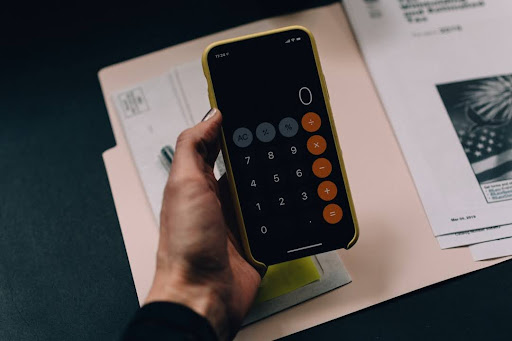 calculator and someone calculating how much money they will save.